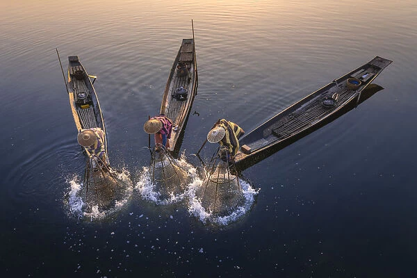 Elevated view of three fishermen catching fish from boats using traditional conical nets