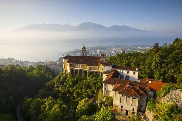 Elevated view over the picturesque Sanctuary of Madonna del Sasso illuminated at sunrise