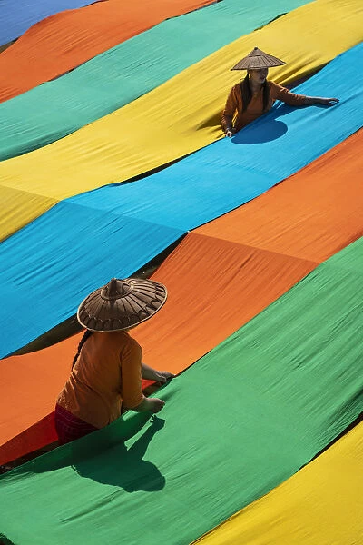 Elevated view of two women hanging long pieces of dyed fabric to dry, Lake Inle