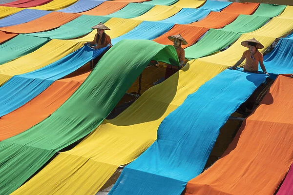 Elevated view of three women hanging long pieces of dyed fabric to dry, Lake Inle