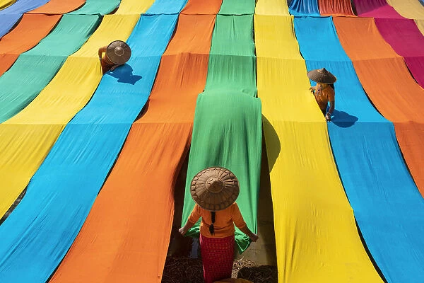 Elevated view of three women hanging long pieces of dyed fabric to dry, Lake Inle