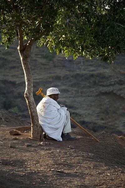 Ethiopia, Lalibela. An old man rests beneath a tree in the early morning light