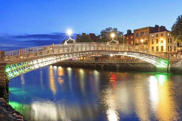 Europe, Dublin, Ireland, Halfpenny bridge reflecting on the Liffey river by night