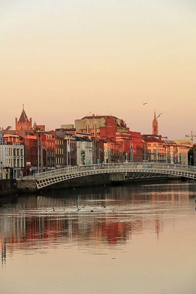 Europe, Dublin, Ireland, Halfpenny bridge at sunrise with buildings reflecting in