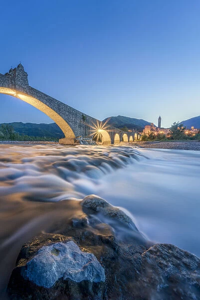 Europe, Italy, Emilia Romagna: Bobbio, falls on the Trebbia river and the medieval town at twilight
