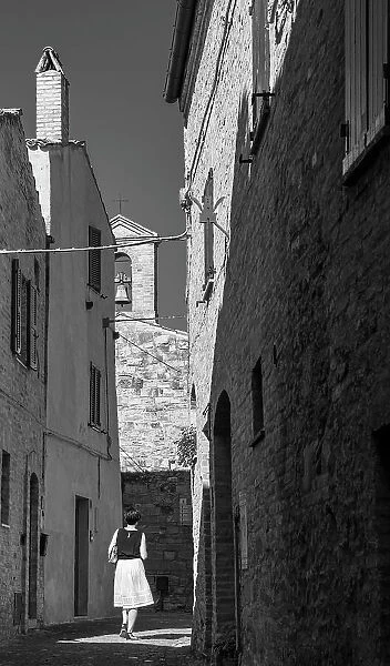europe, Italy, The Marches. A woman walking in a narrow street in the beautiful hamlet of Torre di Palme near Fermo