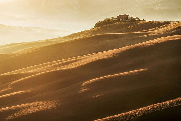 Farmhouse on top of a hill at sunrise in Tuscany, Italy