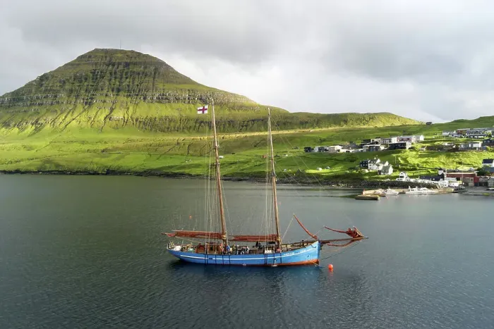 Framed Print : The Faroese-built wooden sailship Norðlysið (The Nordic Lights) sailing in fron of the village of Syðrugota. Island of Eysturoy. Faroe Islands