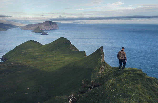 Faroese guy walking along Knukur mountain in Mykines. Faroe Islands