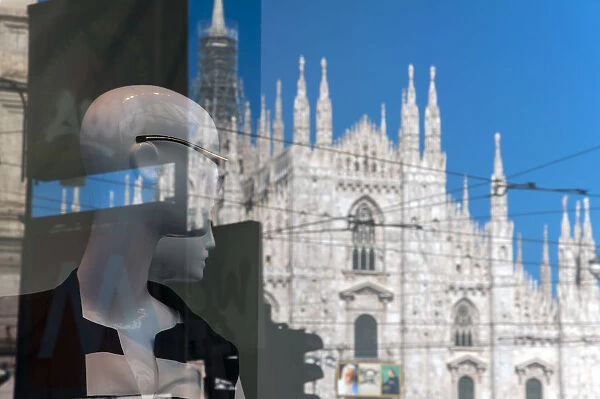 Fashion dummies seem watching Duomo cathedral reflected in the shop window, Milan, Italy