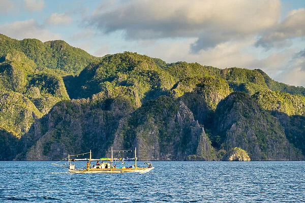 Filipino outrigger fishing boat and dramatic karst landscape of Coron Island, Palawan