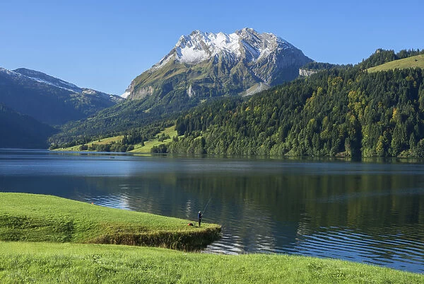 Fisherman at Lake Wagital with Fluebrig mountain in the Glarner Alps at fall