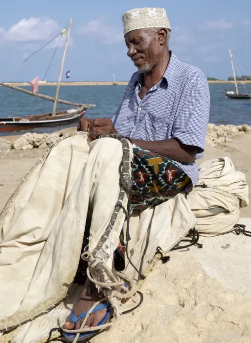 Framed Print : A fisherman repairs the sail of his wooden sailing boat Framed Print : A fisherman repairs the sail of his wooden sailing boat