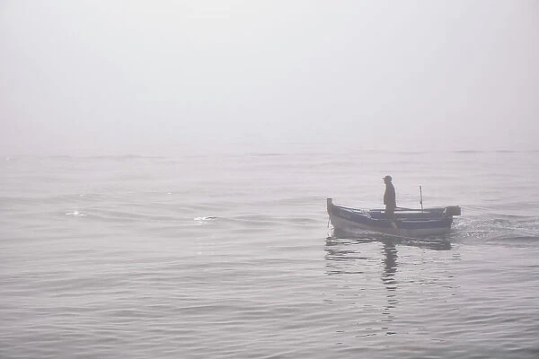 Fishing boat in a foggy morning coming from the sea. Setubal, Portugal