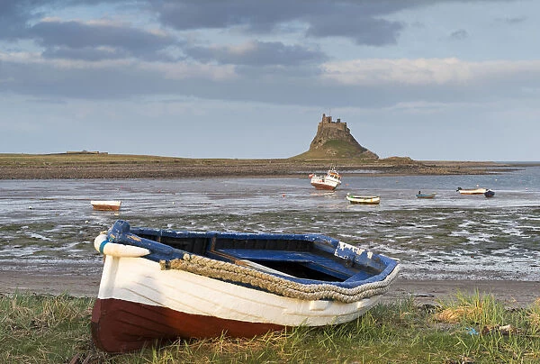 Fishing boat pulled onto the shore at Holy Island, looking towards the castle, Lindisfarne