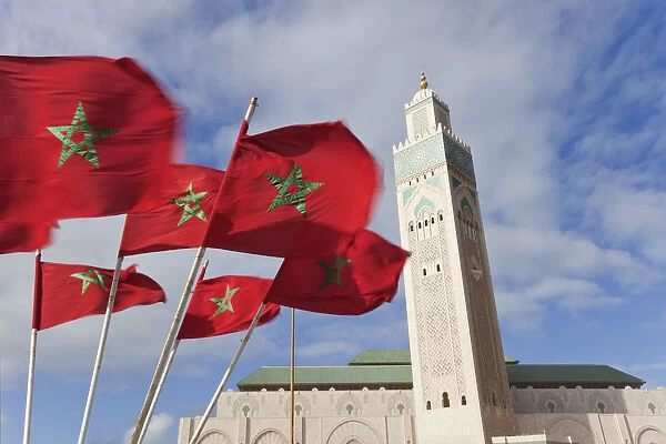 Flags of Morocco waving in the wind and Hassan II Mosque, the third largest mosque