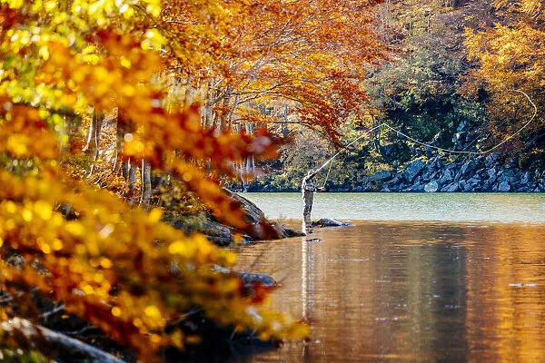 Fly fishing by an autumn forest in Lago Santo Modenese, Modena, Emilia Romagna, Italy