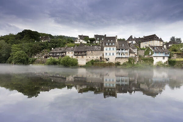 France, Correze, Argentat, Old houses and a layer of mist are reflected in the Dordogne