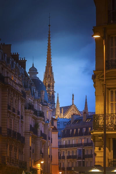 France, Paris, Notre Dame Cathedral, spire above rooftops at dusk