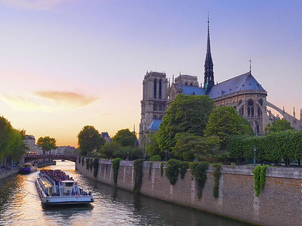 France, Paris, Notre Dame Cathedral, Torboat on River Seine at dusk