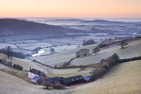Frost coated countryside and farm buildings at sunrise, Exe Valley, Devon, England