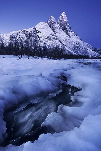 Frozen river and Mt. Otertinden taking the first lights of the day, Tromso region, Norway