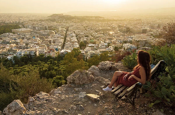Girl seated on a bench at the Viewpoint of Athens at the lycabettus mount, Athens, Greece