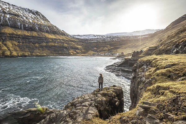 Girl standing along the fjord close to Tjornuvik. Streymoy island, Faroe islands