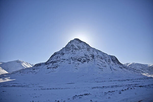 Glen Coe, Scotland. The sun hides behind Meall Mor in snow covered Glen Coe