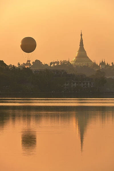 The golden stupa of the Shwedagon Pagoda and the Mingalarbar hot air baloon reflected in