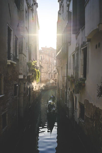 A gondola cruising a little canal during the morning in Venice, Veneto, Italy