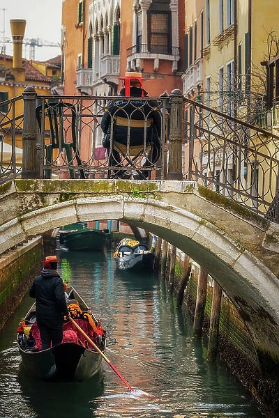 Gondolier rowing a gondola in a canal, Venice, Veneto, Italy