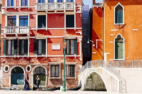 Gondoliers and typical buildings with bridge over canal, Venice, Veneto, Italy