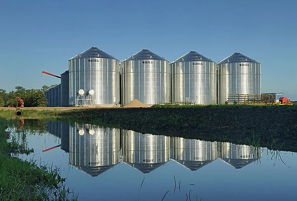 Grain bins refelcted in a pond Lorette, Manitoba, Canada
