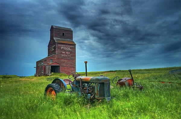 Grain elevators and old tractors in ghost town Bents, Saskatchewan, Canada