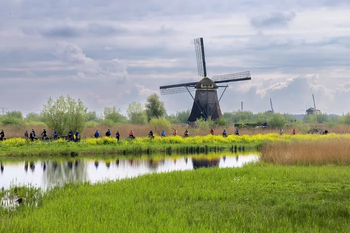 Framed Print : A group of cyclists pass by a windmill at Kinderdijk, South Holland, Netherlands Framed Print : A group of cyclists pass by a windmill at Kinderdijk, South Holland, Netherlands