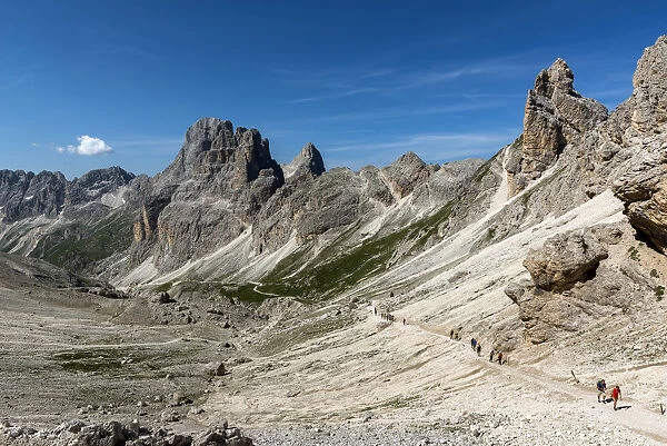 A group of hikers in the Vajolet Valley with the peaks of the Catinaccio group, Dolomites