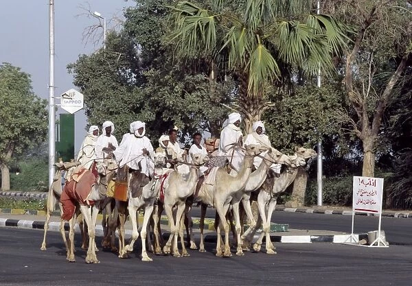 A group of men ride their camels up a main street in Khartoum