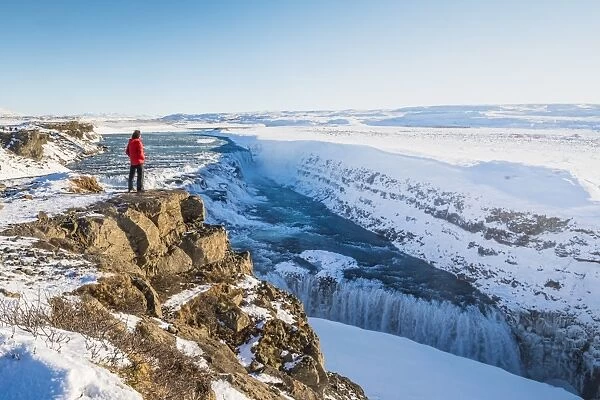 Gullfoss waterfall, Golden Circle, Iceland. Man with red coat admiring the waterfall (MR)