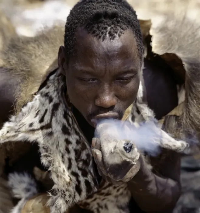 Framed Print : A Hadza hunter smokes cannabis from a crude stone pipe Framed Print : A Hadza hunter smokes cannabis from a crude stone pipe