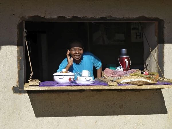 A happy Malagasy woman at the counter of her small