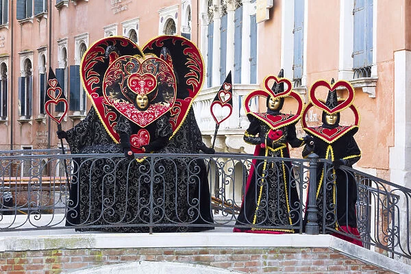 Heart-shaped costumes posing on a bridge at the Venice Carnival, Venice, Italy