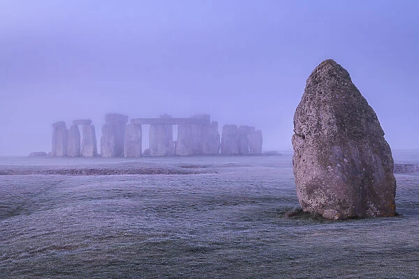 The Heel Stone and Stonehenge at dawn on a misty, frosty morning, Wiltshire, England. Winter (January) 2022