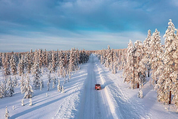 High angle car driving on an icy road among trees covered with snow, Kangos, Lapland, Sweden