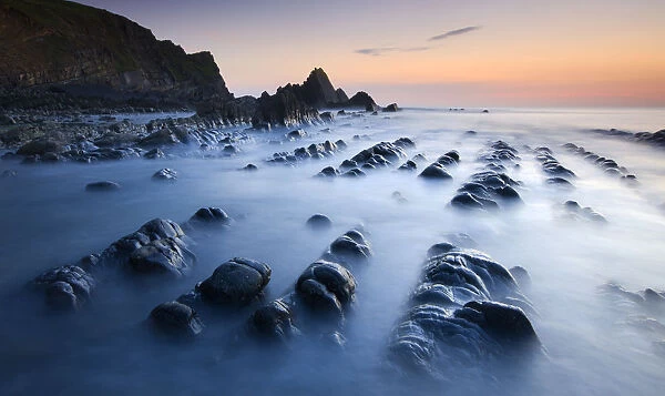 High tide gradually submerges the rocky shores of Blegberry Bay at sunset, Hartland