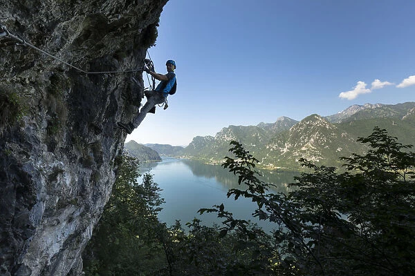 a hiker is climbing along the Ginestre klettersteig with the lake Idro in the background