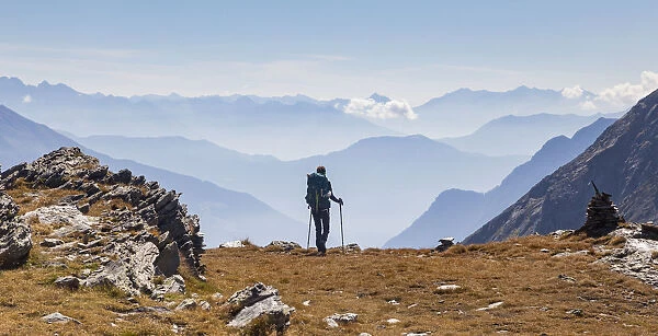 Hiker looking to the mountainscape and mountain profiles in background in Swiss Alps