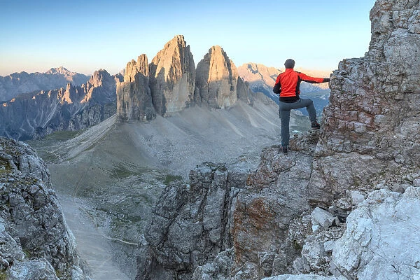 Hiker on the top of mount Paterno  /  Paternkofel looking the sunrise towards Tre Cime