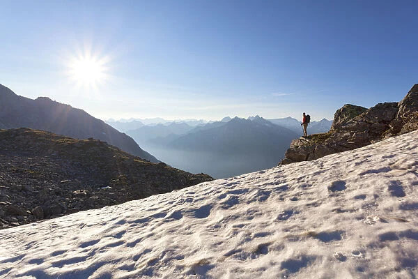 A hiker on the snowfield under the summit of Peterskopfl, Zillertal Alps