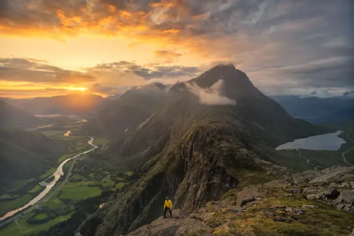 Framed Print : Hiker walking on Romsdalseggen ridge over Rauma valley lit by sun rays at sunset